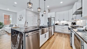 A modern kitchen with white cabinets, stainless steel appliances, and a central island. - ULTIMATE LUXURY ON THE WATER! PRIVATE POOL AND HOT TUB! (Gulf Shores)