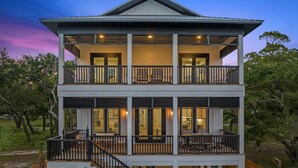 A two-story house with a balcony on the upper floor, a covered outdoor seating area, and a staircase leading to the upper level. - ULTIMATE LUXURY ON THE WATER! PRIVATE POOL AND HOT TUB! (Gulf Shores)