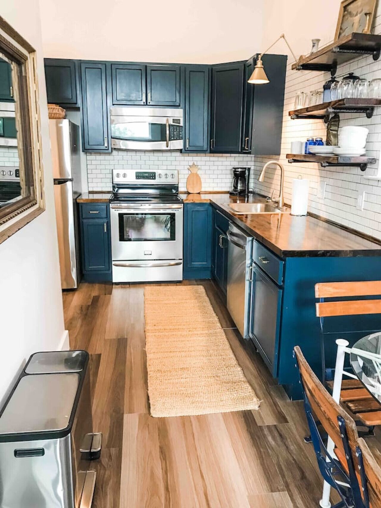A compact kitchen with dark blue cabinets, stainless steel appliances, and a wooden countertop.