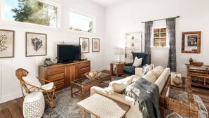 A spacious living room with a large TV, comfortable seating, and a view of trees through the windows. - 1BR Apt. w/ KING Bed on 30A! - .4 mi to Beach (Santa Rosa Beach)