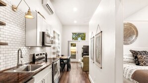 A modern kitchen with white cabinets, a wooden countertop, and a dining area with a table and chairs. - On 30A! New 1BR Apt. w/ KING 10min walk to beach! (Santa Rosa Beach)