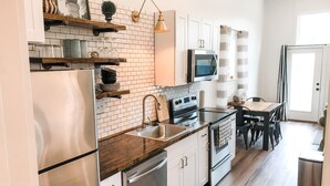 A modern kitchen with white cabinets, stainless steel appliances, and a wooden countertop. - On 30A! New 1BR Apt. w/ KING 10min walk to beach! (Santa Rosa Beach)
