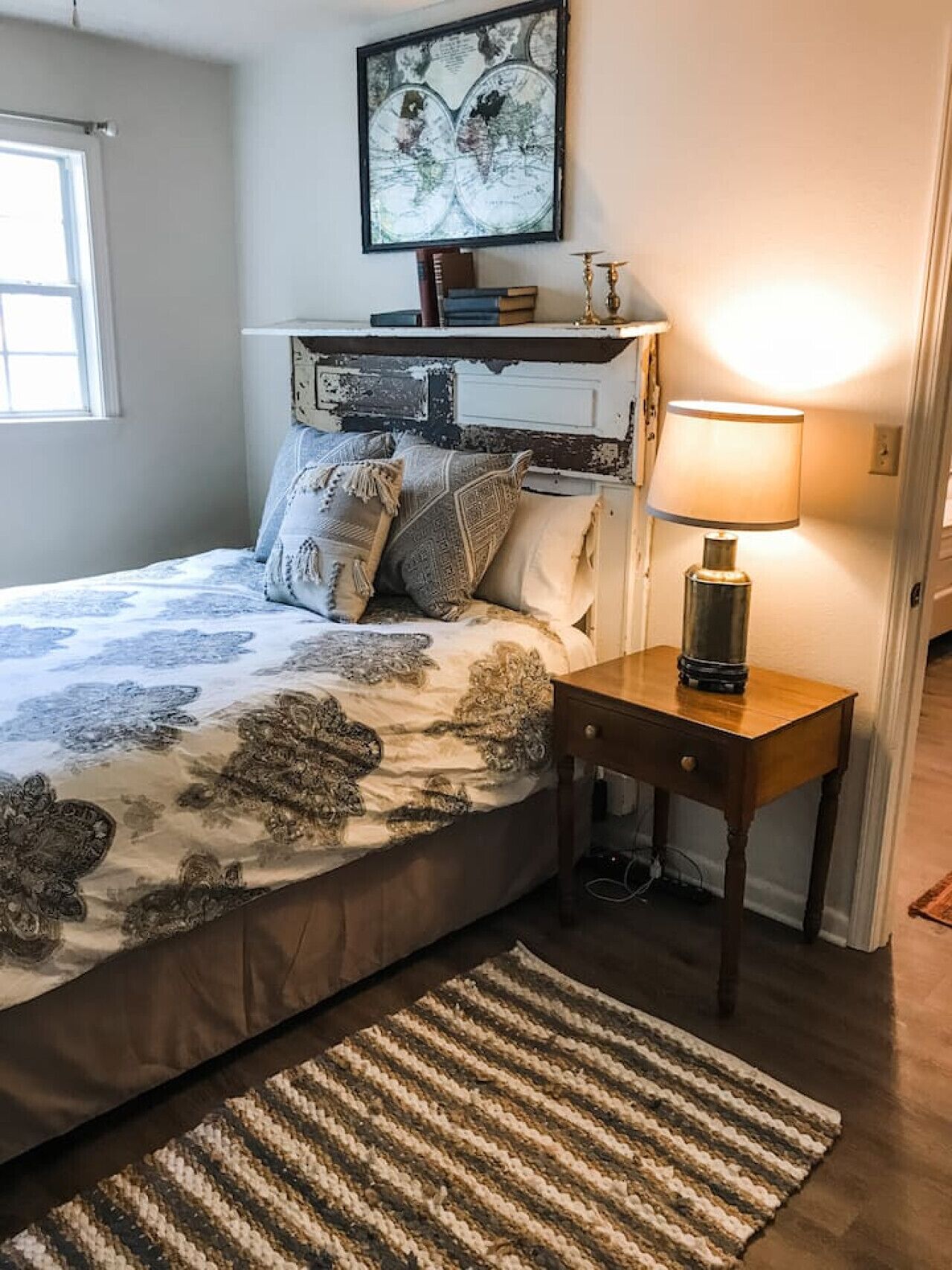 Une chambre à coucher avec un lit, une table de chevet avec une lampe, une carte du monde accrochée au mur et une fenêtre.
