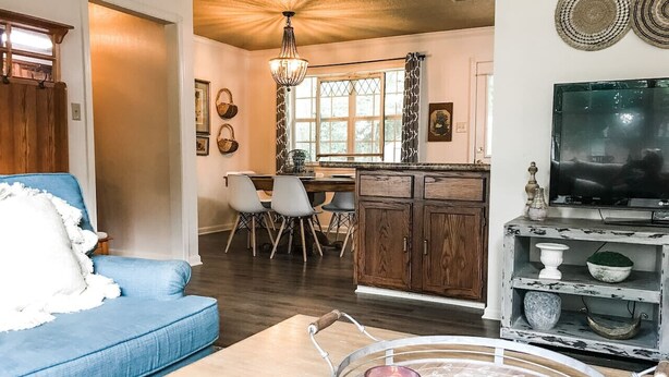 Una sala de estar con un sofá azul, una mesa de centro de madera y un mueble para la televisión.