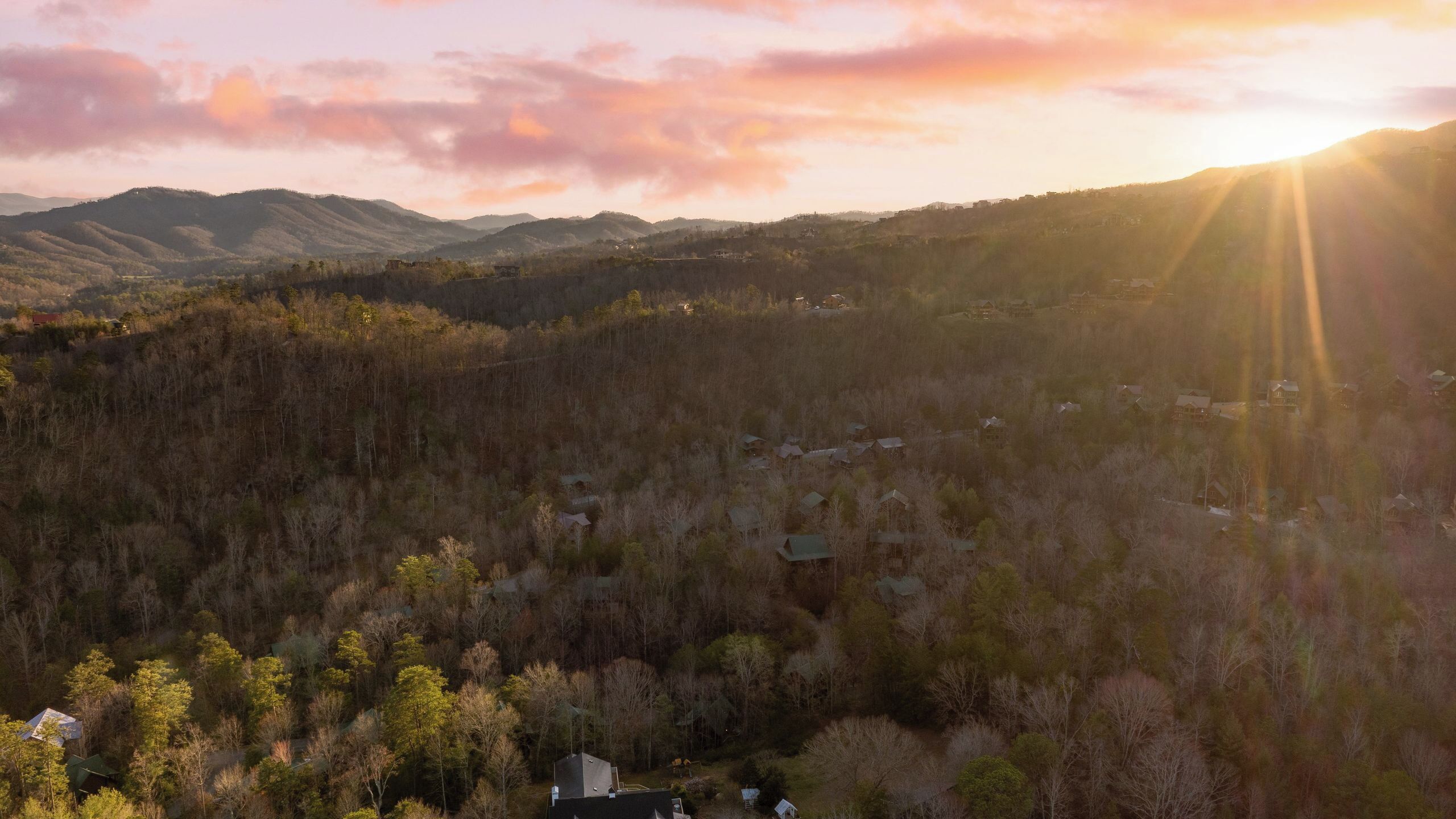 A mountainous landscape with scattered houses and dense forest.