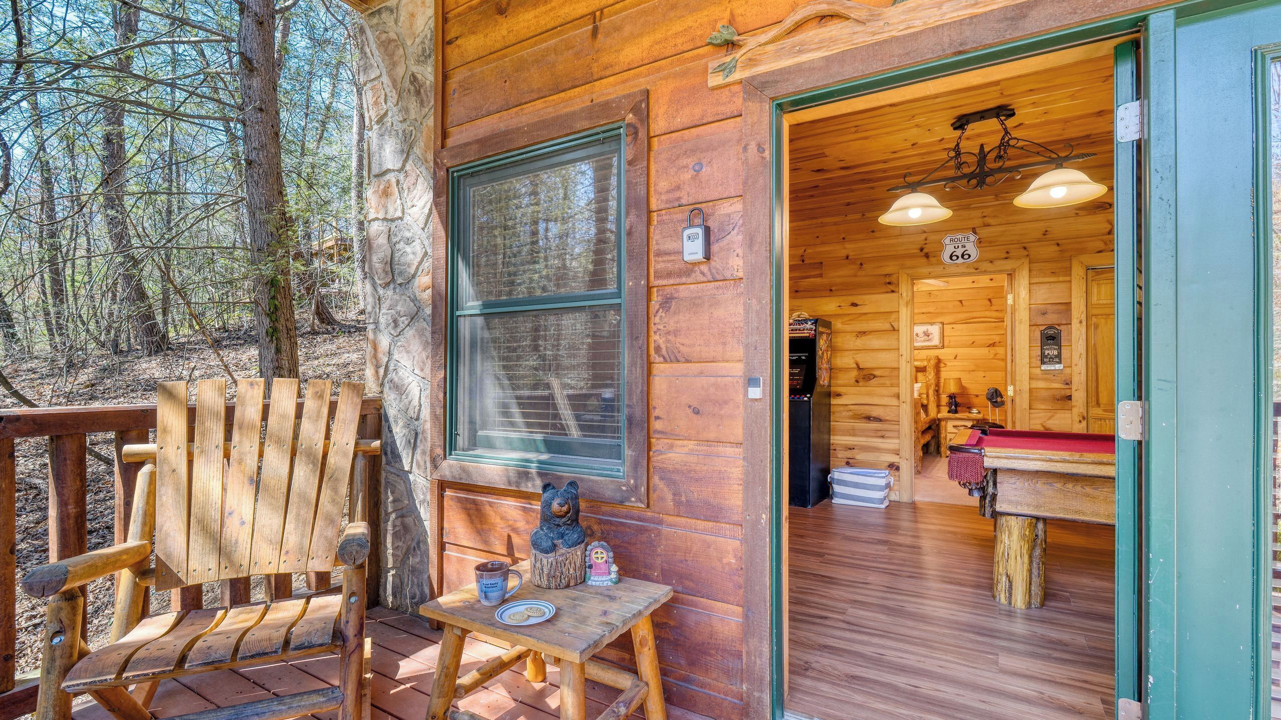 A wooden cabin with a porch, a table with a bear figurine, and a view of the interior.