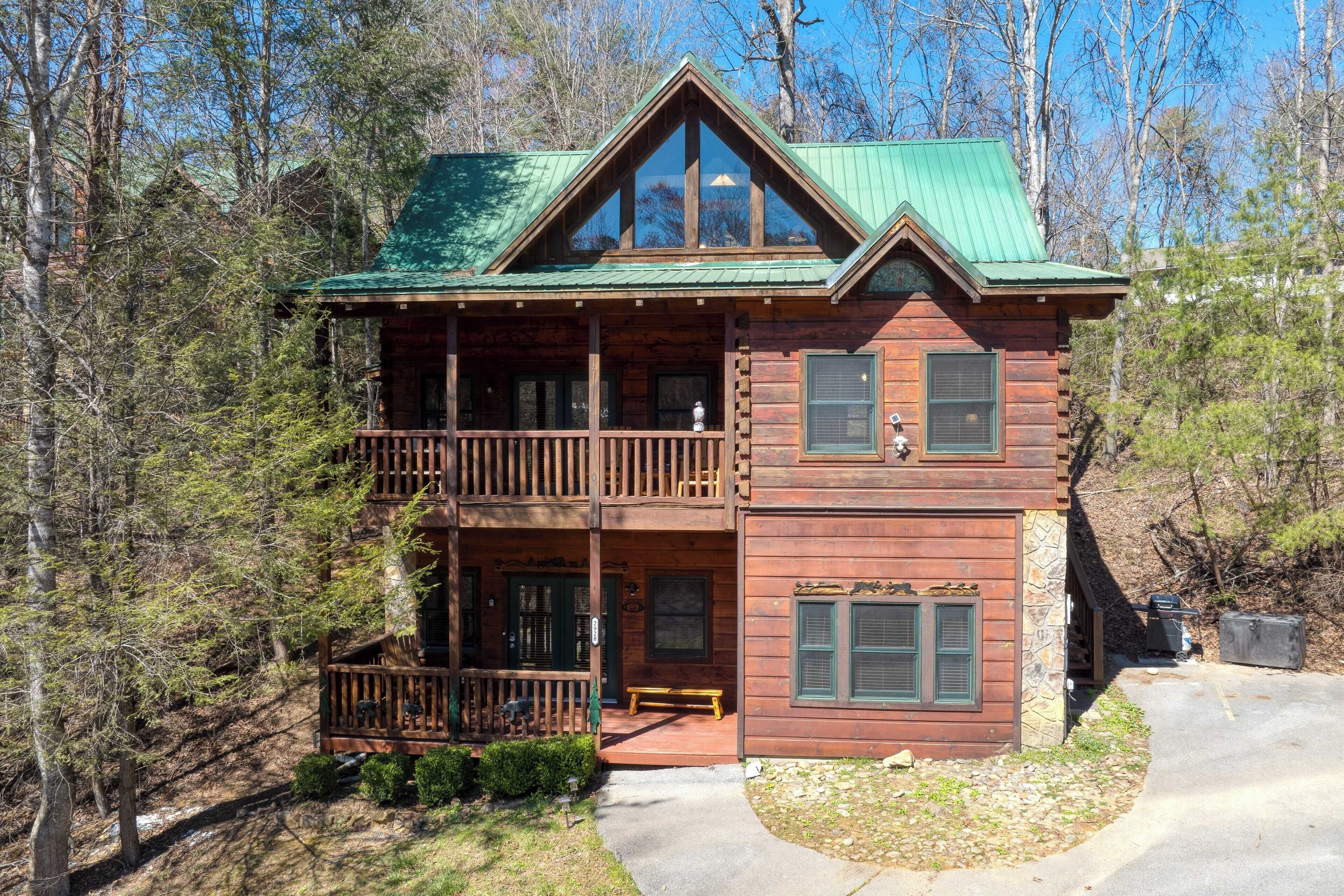 A two-story log cabin with a balcony, a front porch, and a stone foundation.