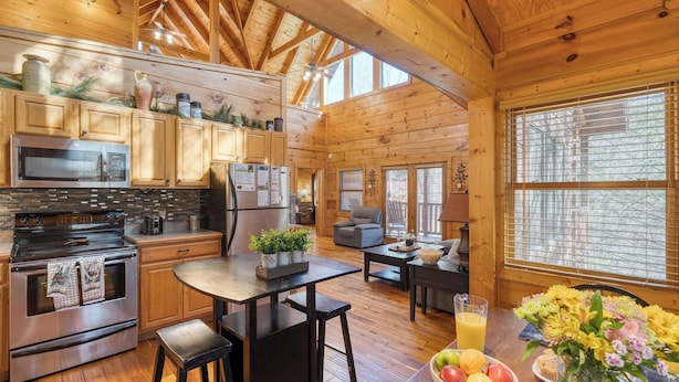 A spacious kitchen with modern appliances, wooden cabinetry, and a dining area with a table and chairs. - Four Bears Lodge by Avantstay Hot Tub, Game Room, Views Near Pigeon Forge (Sevierville)