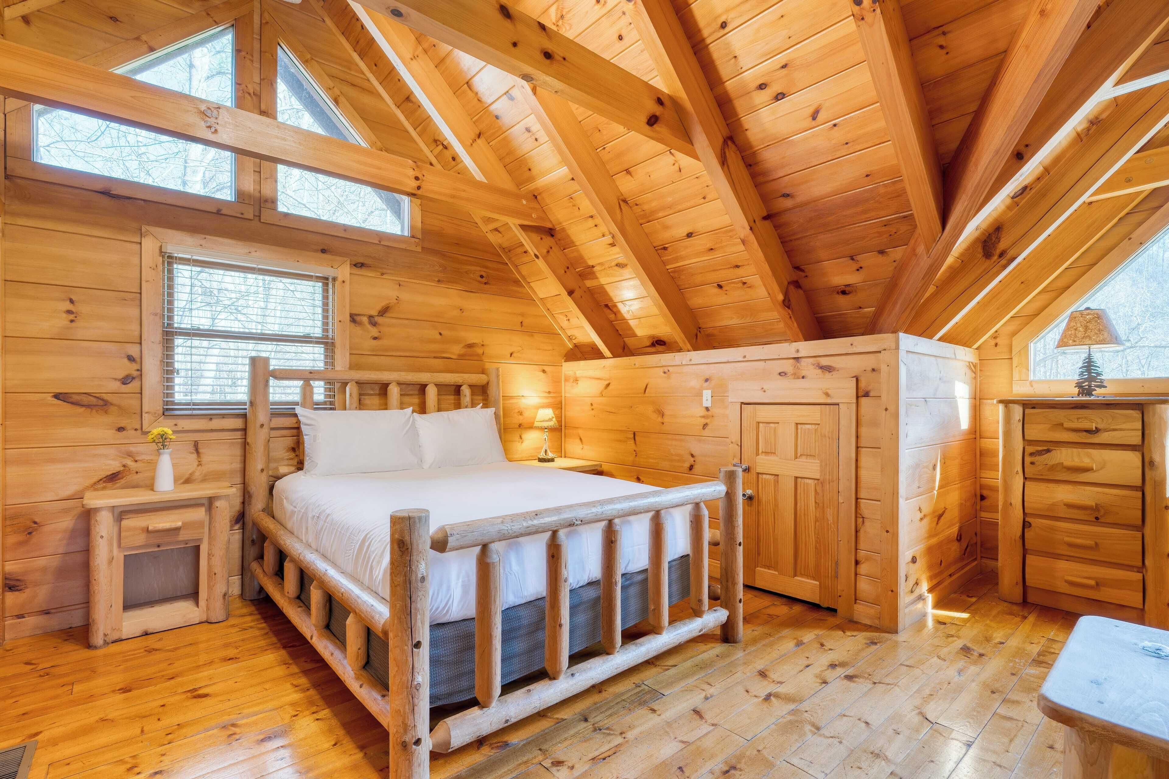 Ein Schlafzimmer einer Holzhütte mit Bett, Nachttisch und Fenster.