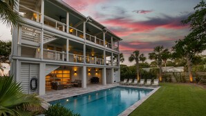 Uma casa de dois andares com piscina, área de estar ao ar livre e vista para o pôr do sol.