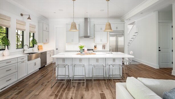 A modern kitchen with a central island, bar stools, and pendant lighting.
