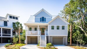 A two-story house with a front porch, a staircase leading to the entrance, and a driveway.
