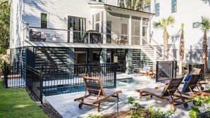 Une maison à deux étages avec une piscine, un espace salon extérieur et un patio couvert.