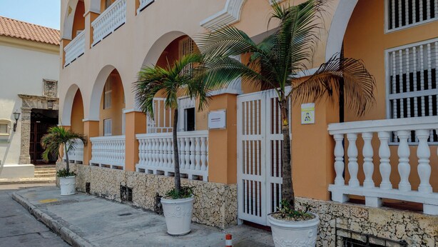 Un immeuble doté de nombreux balcons, de grands pots de plantes et d’une façade en pierre.