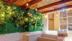 Un espace spa doté d’un plafond en bois, d’un mur recouvert de verdure et d’un coin salon offrant une vue sur l’extérieur.