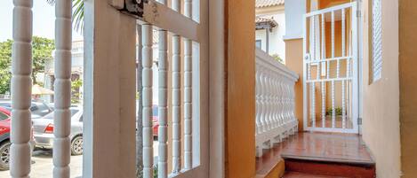 A staircase with a white railing and red steps leading to a door with a metal gate.