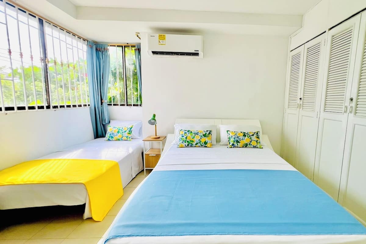 A room with a bed, a small table, a lamp, and a window with curtains.