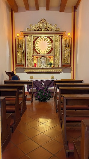 An interior of a church with a central altar, pews, and a tiled floor.