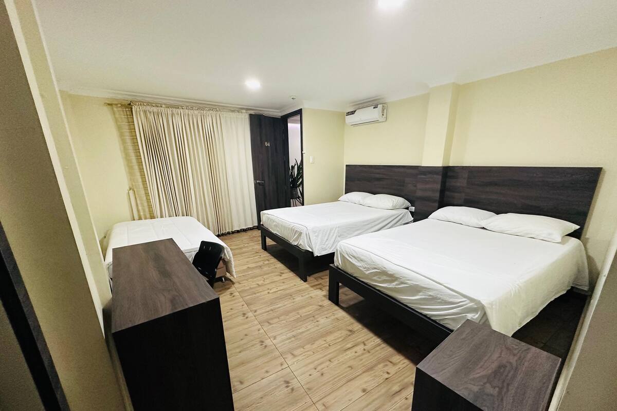 Een hotelkamer met twee enkele bedden, een houten vloer, een bureau en een stoel.
