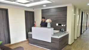 A reception area with a modern design, featuring a reception desk, a vase with flowers, and a phone. - Hotel Vivanco's (Huaquillas)