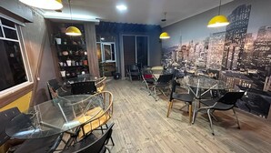 A modern conference room with glass tables and chairs, wooden flooring, and a cityscape mural on the wall. - Hotel Vivanco's (Huaquillas)