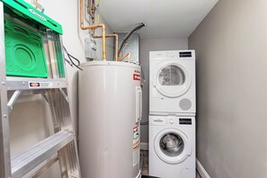 Convenient laundry facility with a large water heater, washing machine, and dryer.