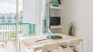 A balcony with a table, chairs, a TV, and plants.
