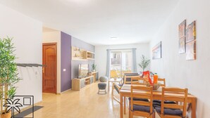 Una sala de estar moderna con comedor, cocina y un amplio ventanal que proporciona luz natural.