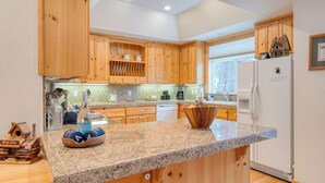 Una cocina con armarios de madera, encimeras de granito, lavavajillas integrado y un refrigerador.