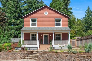 Une maison à deux étages avec un porche à l’avant, le numéro « 315 » sur la porte et un escalier en pierre menant à l’entrée.