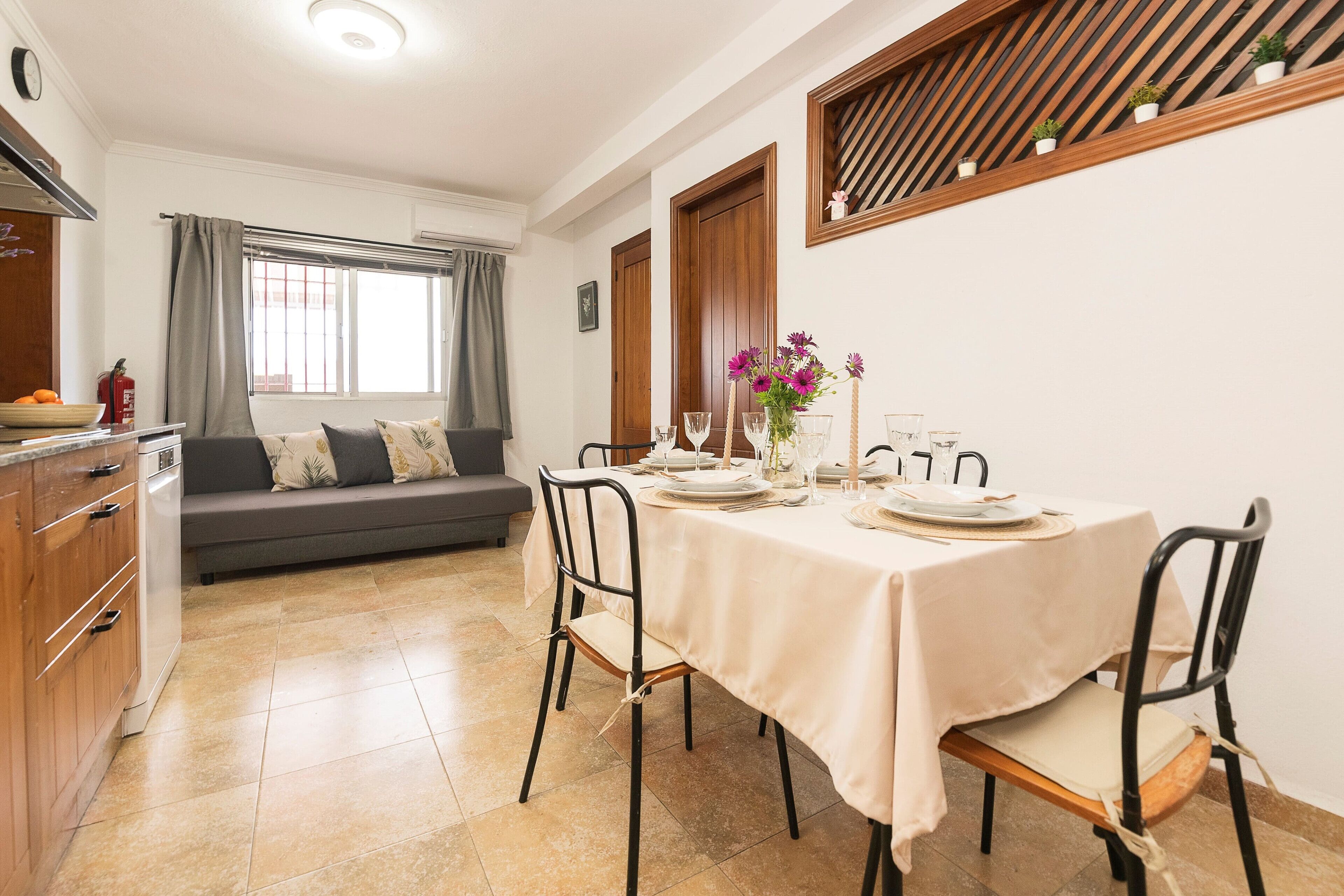 Een eetgedeelte met een tafel voor vier personen, een bank en een keuken met kastjes en een spoelbak.