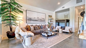 A modern living room with a sofa, coffee table, and a large potted plant. - Midnight Eddy @ Water's Edge: Lake front~Hot Tub~Fire pit~Kayaks~more (Fayetteville)