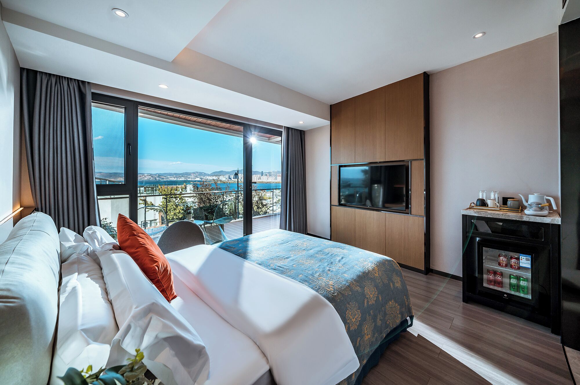 Een moderne hotelkamer met een groot bed, een televisie, een minibar en een balkon met uitzicht over de stad.