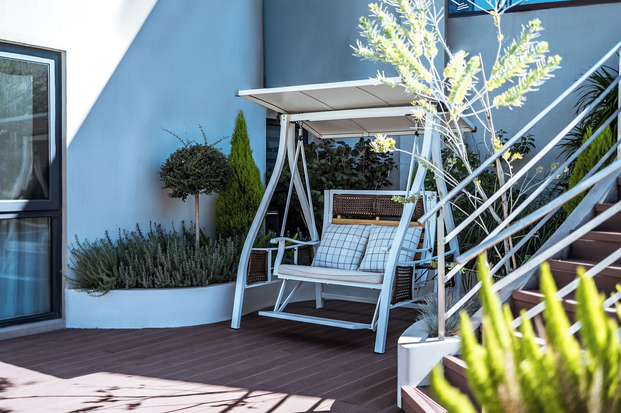 A modern outdoor seating area with a swing chair, a small table, and a pergola.