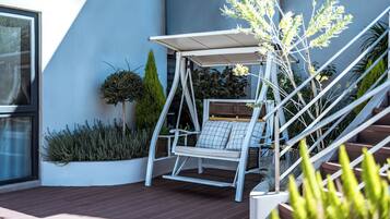 A modern outdoor seating area with a swing chair, a small table, and a pergola.