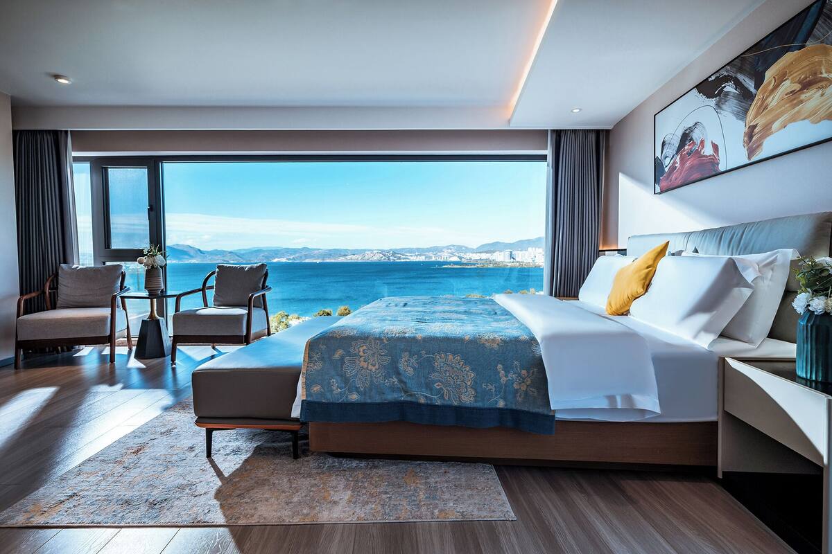 Een moderne slaapkamer met een groot bed, een zithoek en uitzicht op zee.