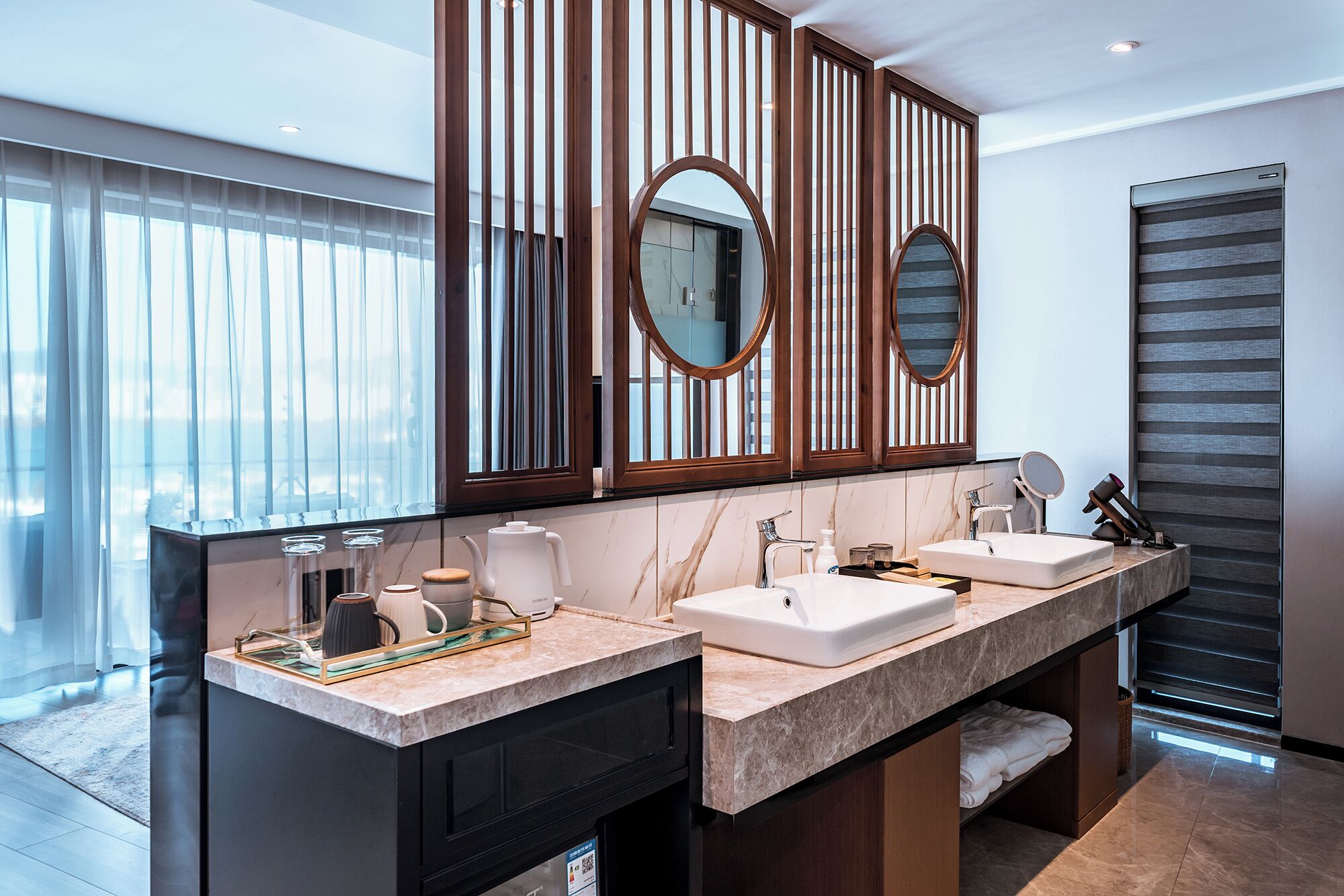 A modern bathroom with two sinks, a large mirror, and a wooden partition.