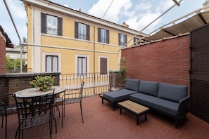 A patio with a round table, chairs, a sofa, and a small potted plant.