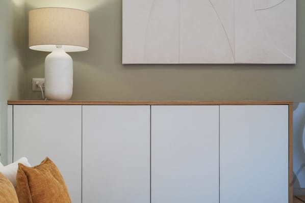 A bedroom with a bed, a bedside lamp, a wall-mounted artwork, and a wardrobe.