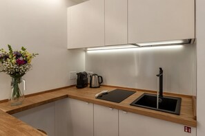 A modern kitchen with a wooden countertop, a black sink, a coffee maker, and a vase of flowers.