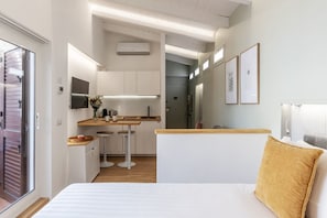 A compact hotel room with a bed, a kitchenette, and a small dining area.