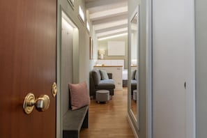 A hallway with a wooden door, a bench, and a seating area with ottomans and cushions.