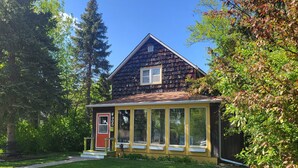 A two-story house with a porch, a red door, and a number 905 on the side.