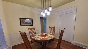 A dining room with a round wooden table, six wooden chairs, and a chandelier.
