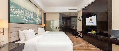 A hotel room with a large bed, a desk with a computer, a TV, and a large painting on the wall.