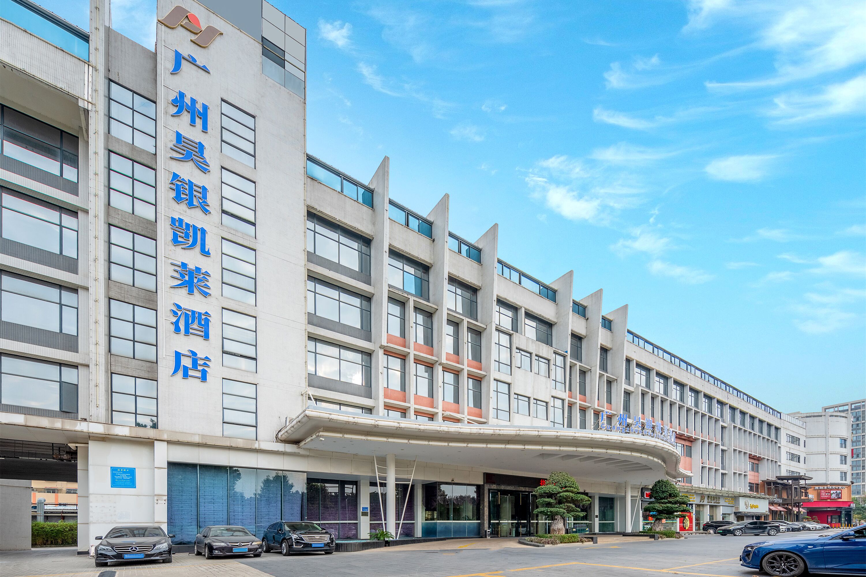 Un hotel con fachada moderna, varios pisos y un área de entrada cubierta.