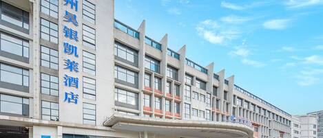 Un hotel con fachada moderna, varios pisos y un área de entrada cubierta.