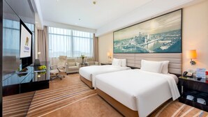 Habitación de hotel con dos camas, televisión, escritorio y un ventanal grande.