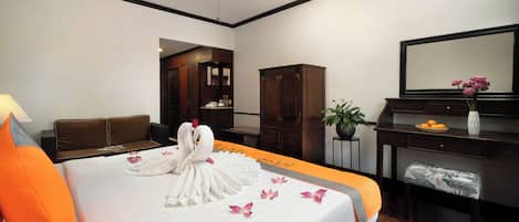Una habitación de hotel con una cama bien hecha, un sofá, un escritorio con un florero y un ventilador de techo.