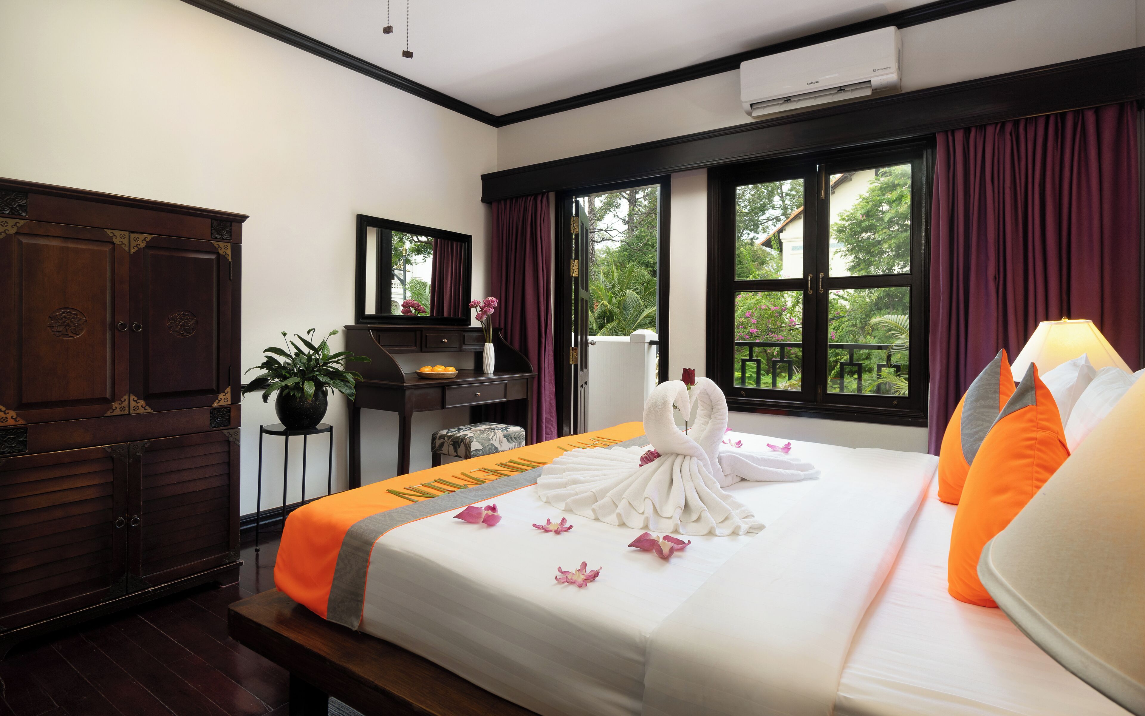 A hotel room with a bed, a desk, a wardrobe, and a window with curtains.